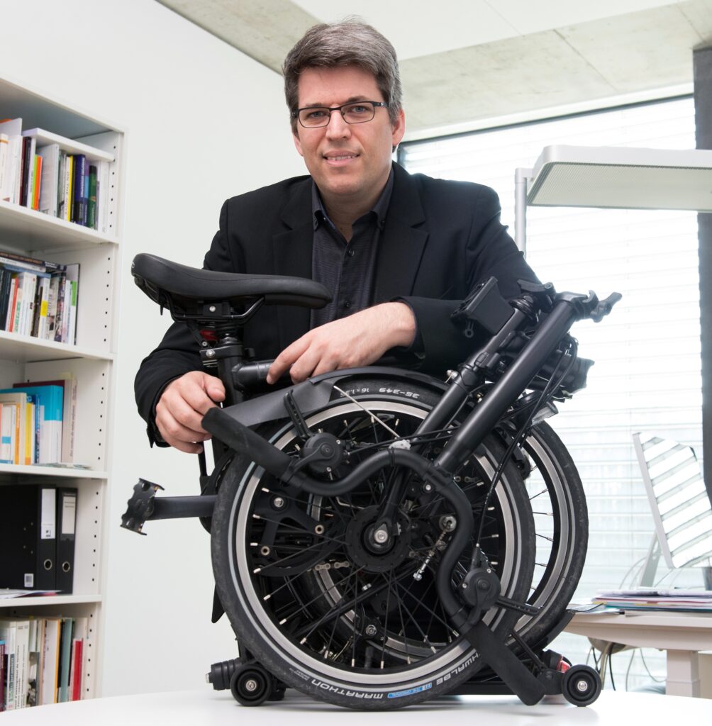 Image of researcher Patrick Rérat with a foldable bicycle. 