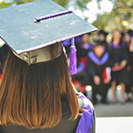 Woman in graduation hat, standing in front of her peers.