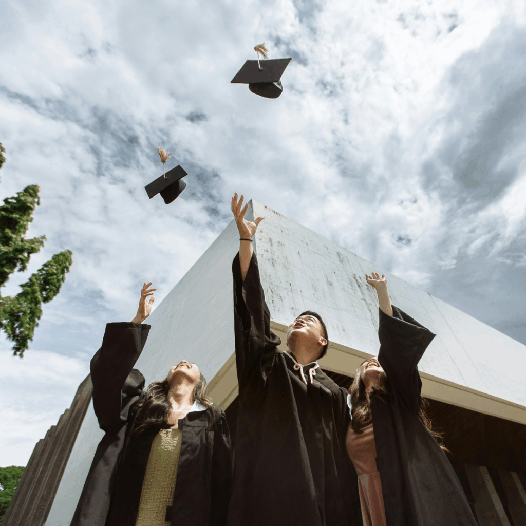 image of university students throwing their graduation caps into the sky