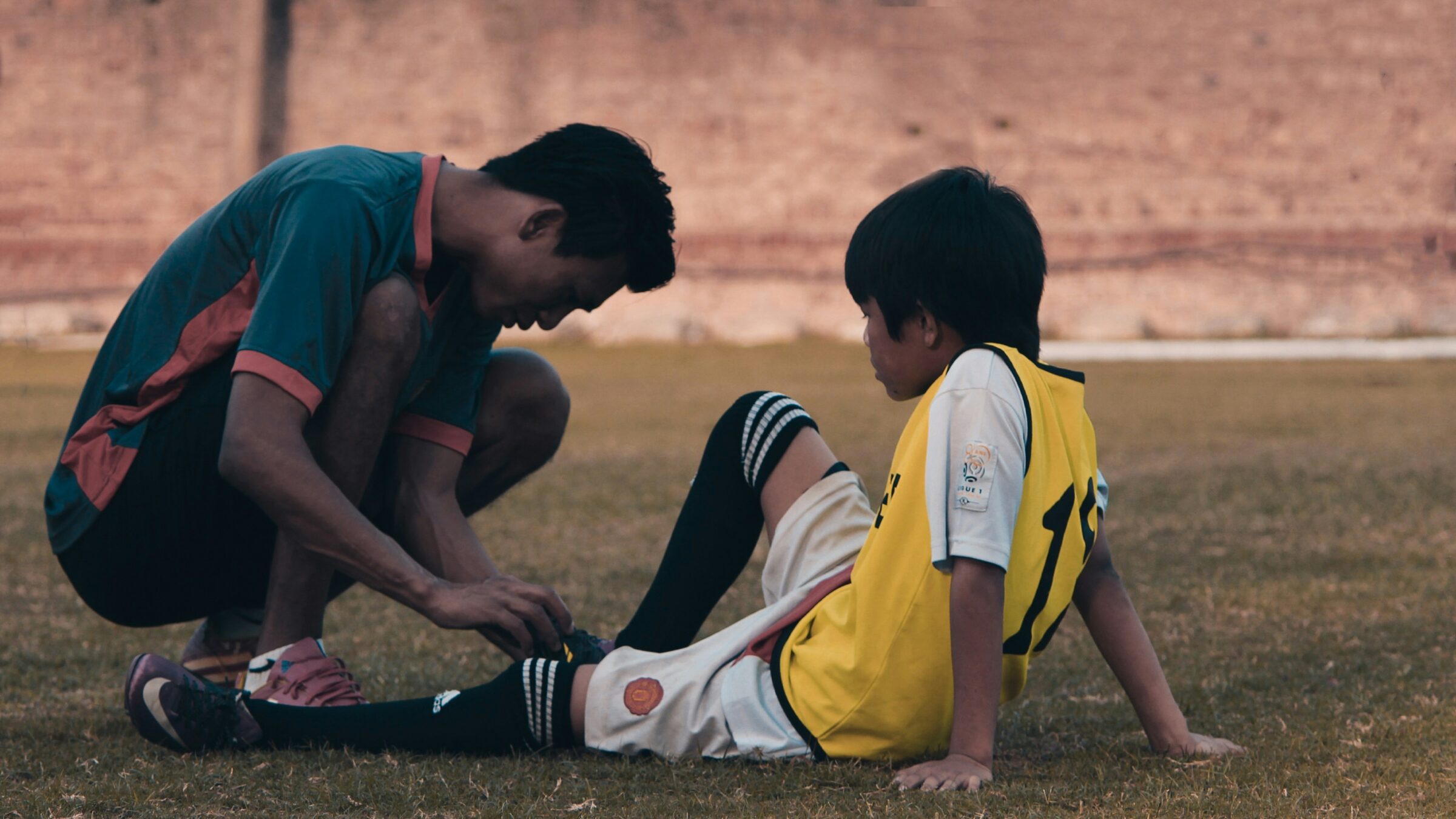 soccer player helping an injured team mate on the field